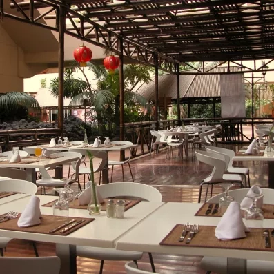 Une terrasse de restaurant ombragée par une pergola en bois, offrant un cadre convivial pour dîner en extérieur.