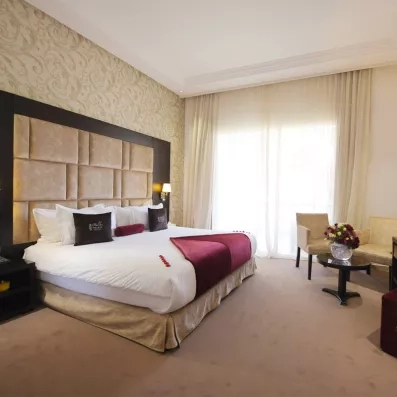 lit double lit double avec une tête de lit en tissu et en bois marron et juste à côté une fenêtre 