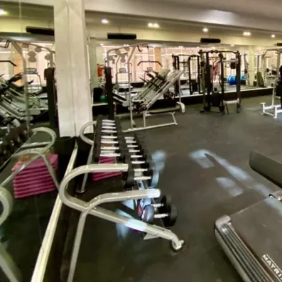 salle de sport bien équipée et avec des miroirs sur les murs qui entoure