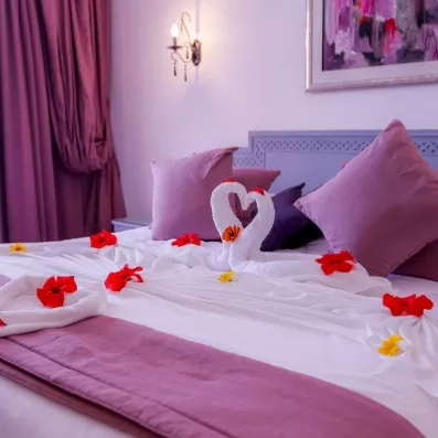 Lit double avec cygnes en serviettes et fleurs pour un séjour romantique à l'hôtel Al Jazira