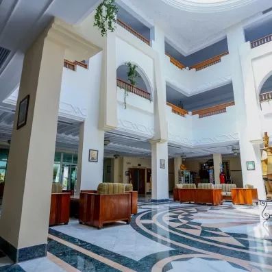 Grand hall de réception lumineux avec colonnes, balcons intérieurs et sol en marbre à Djerba.