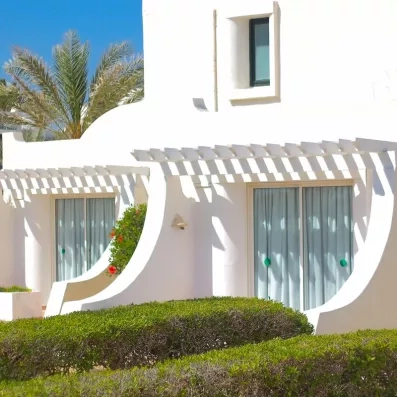 Détail des bungalows blancs avec pergolas et rideaux légers offrant une atmosphère de vacances relaxantes.