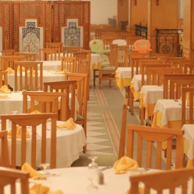 Salle de restaurant spacieuse de l'hôtel Al Jazira avec tables dressées et décoration orientale traditionnelle.