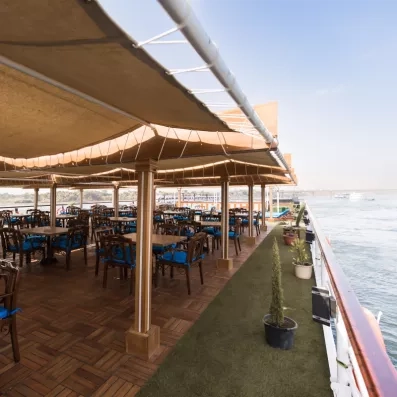 Restaurant extérieur ombragé sur le pont d'un navire, gastronomie et vue sur le fleuve Nil.