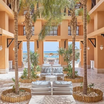 Lobby luxueux avec palmiers intérieurs et vue mer au Premier Le Rêve Hôtel & Spa, Égypte.