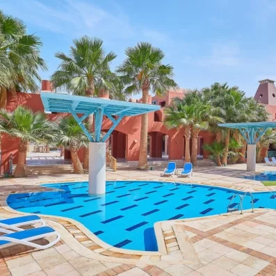 Piscine extérieure azur avec parasols modernes et palmiers pour un séjour détente à Hurghada.