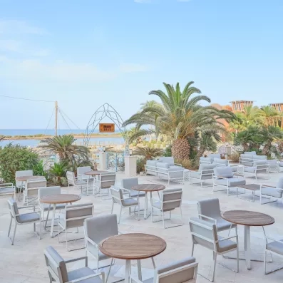 Salon extérieur avec fauteuils confortables et palmiers, détente au Premier Le Rêve Resort Hurghada.