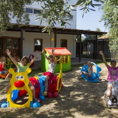 Des enfants s'amusent sur des jeux en plastique dans une aire de jeux de jardin.