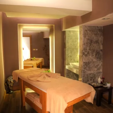 Une salle de massage sereine et bien éclairée, avec deux tables dressées.