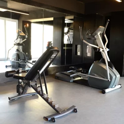 Une salle de sport bien équipée avec des machines et un banc de musculation.