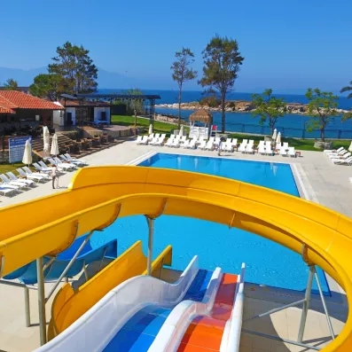Une vue de la piscine de l'hôtel avec des toboggans et des chaises longue.