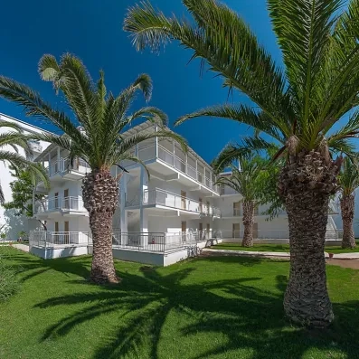 Un bâtiment blanc à l'architecture moderne, entouré de palmiers, sous un ciel bleu.