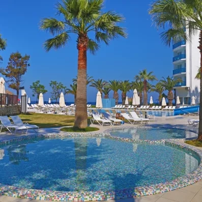 Un espace aquatique avec une pataugeoire et des rangées de transats au pied de l'hôtel.