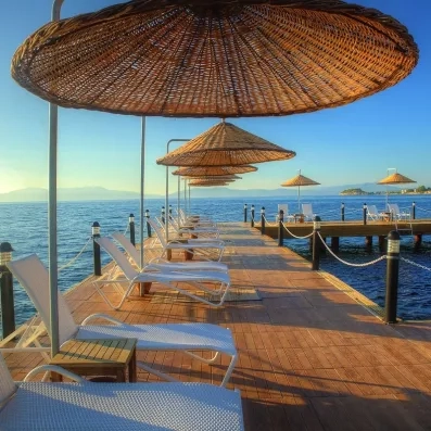 Un ponton de bois s'avançant sur la mer, équipé de bains de soleil et de parasols.