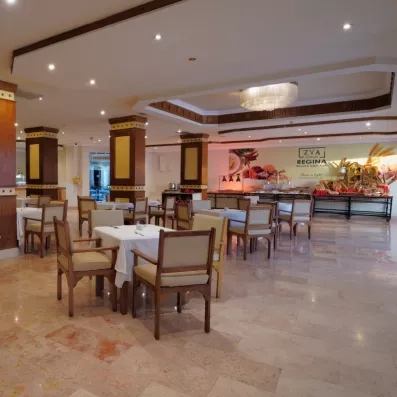 Salle du restaurant principal de l'hôtel avec chaises et tables dressées 