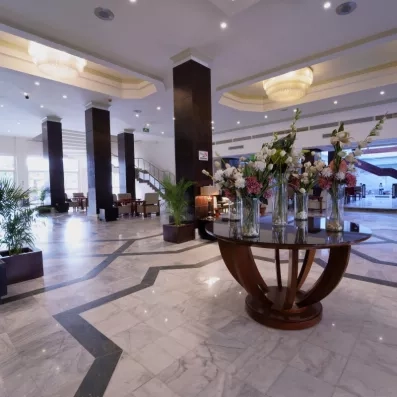 Hall de la réception de l'hôtel, sol en marbre colonnes en bois, table de décoration centrale avec des fleurs
