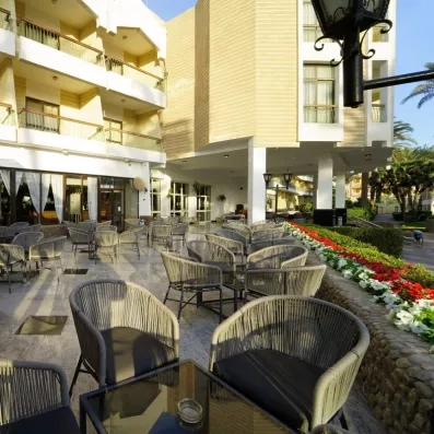 bar terrasse extérieur, bâtiment de l'hôtel, fleurs rouge et blanches, tables et chaises