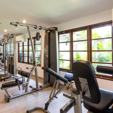 Une salle de sport lumineuse avec divers appareils face à de larges baies vitrées.