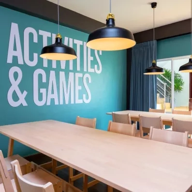 Une salle moderne dédiée aux activités et aux jeux, équipée de grandes tables.