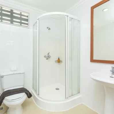Salle de bain, équipée d'une douche et d'un grand miroir au cadre en bois.