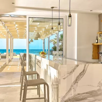 bar du restaurant de la plage, blanc épuré, chaises hautes de bar beige, luminaires, 