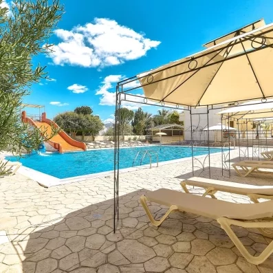 La piscine extérieur de l'hôtel avec toboggans et transats. Ciel bleu au fond 
