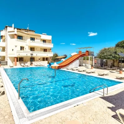 La piscine extérieur de l'hôtel avec toboggans et transats. Ciel bleu au fond  et soleil