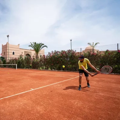 court de tennis en terre battue avec une personne tenant une raquette 