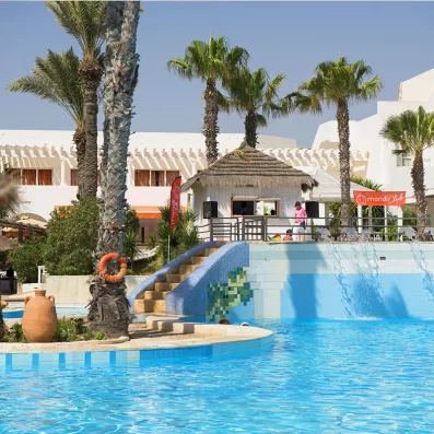 Espace animation au bord de la piscine avec cascade d'eau, paillote et palmiers au Seabel Aladin.