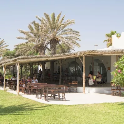 Bar extérieur avec terrasse couverte de chaume et vue sur les jardins de l'hôtel Seabel Aladin Djerba.