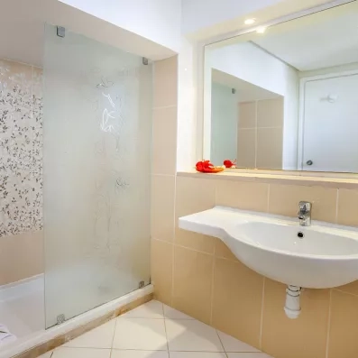 Salle de bains contemporaine du Seabel Aladin Djerba avec douche à l'italienne, paroi vitrée sérigraphiée et vasque blanche design.