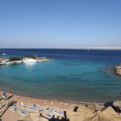 Vue de haut sur la plage, avec des transats sur sable fin et yachts au qaui