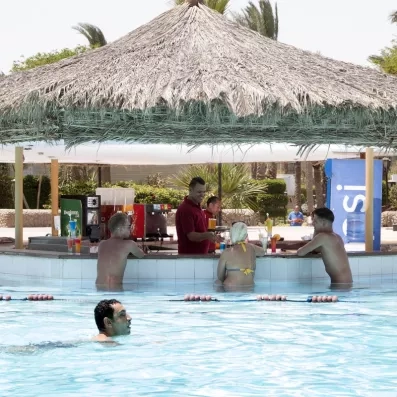 Comptoir de bar au bord de la piscine avec un bar man et des touristes 