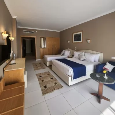 chambre avec 2 lits séparés, tableau décoratif, TV, coiffeuse, tapis, table et fauteuil