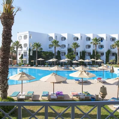 piscine centrale équipée de transats et de parasols avec vue sur le bâtiment de l'hôtel