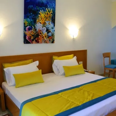 lit avec dessus de lit jaune et bleu et tableau  représentant des coraux 
