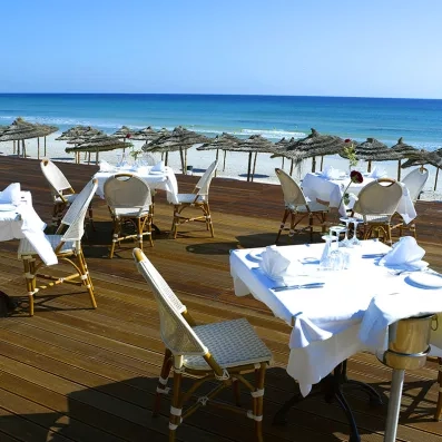 Plusieurs tables dressées sur la terrasse avec vue sur la plage
