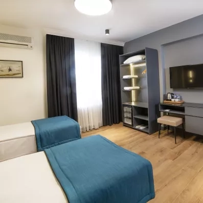 chambre avec deux lits simples et une télévision murale et un dressing