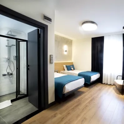 chambre avec deux lits simples et porte accédant à la salle de bain