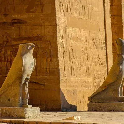 Statue du dieu faucon Horus devant les murs gravés du temple d'Edfou, escale croisière Nil.