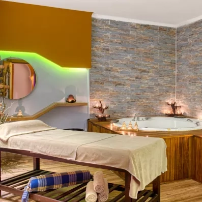 espace de détente avec une table de massage et un jacuzzi