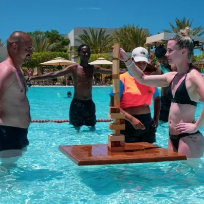 Touristes jouant à un jeu d'équilibre géant dans la piscine ensoleillée du Djerba Aqua Resort, Tunisie.