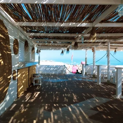 Terrasse ombragée du club de plage privé au César Thalasso Djerba offrant une vue imprenable sur la Méditerranée.