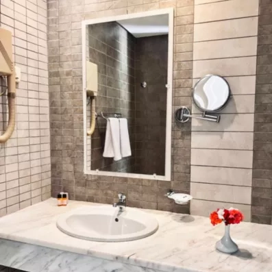 Salle de bain élégante avec vasque en marbre et miroir au César Thalasso à Djerba, Tunisie