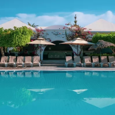Piscine d'eau bleue et transats devant le Connect Bar du Djerba Aqua Resort sous un ciel dégagé.