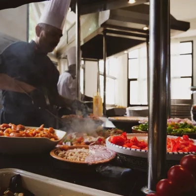 Chefs préparant des plats locaux devant un buffet de légumes frais au restaurant Dar El Hana.