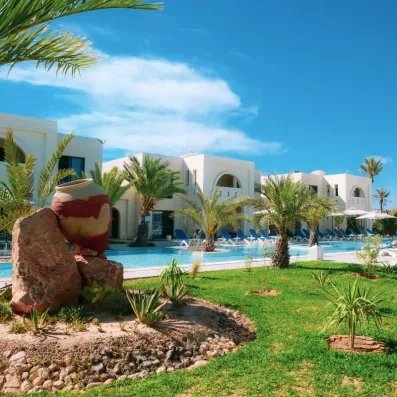 Piscine extérieure lagon entourée de palmiers et d'une architecture traditionnelle sous le soleil de Djerba.