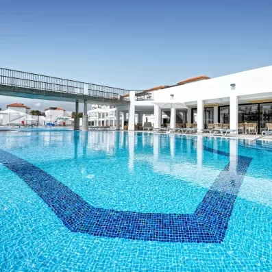 Une grande piscine principale avec une passerelle en arrière-plan et des façades de bâtiments modernes.