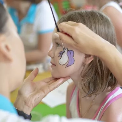 Une enfant se faisant peindre sur la joue lors d'une activité de maquillage.