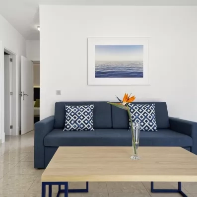 Un coin salon chaleureux décoré d'un tableau marin et de fleurs orangées.